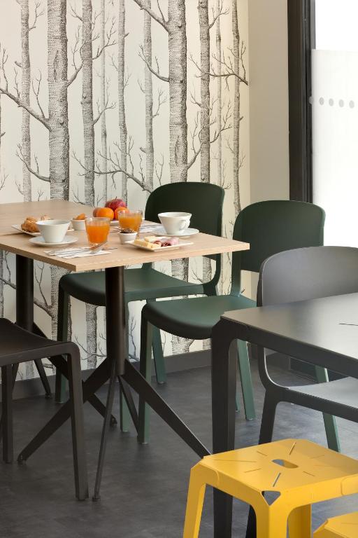 a table and chairs in a room with trees on the wall at Ténéo Apparthôtel Bordeaux Maritime - Cité du vin in Bordeaux