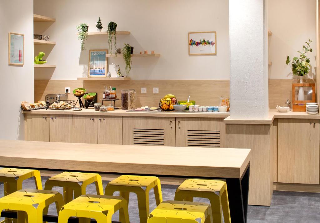 a kitchen with yellow stools and a counter with a counter top at Ténéo Apparthôtel Bordeaux Maritime - Cité du vin in Bordeaux