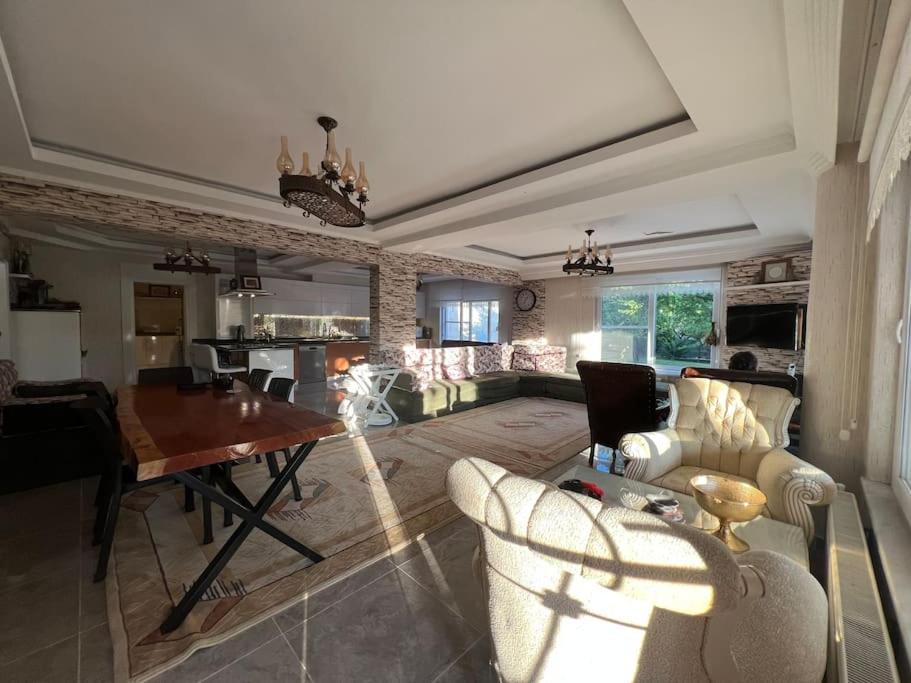 uma grande sala de estar com mesa e cadeiras em Çamlarkent Villaları 