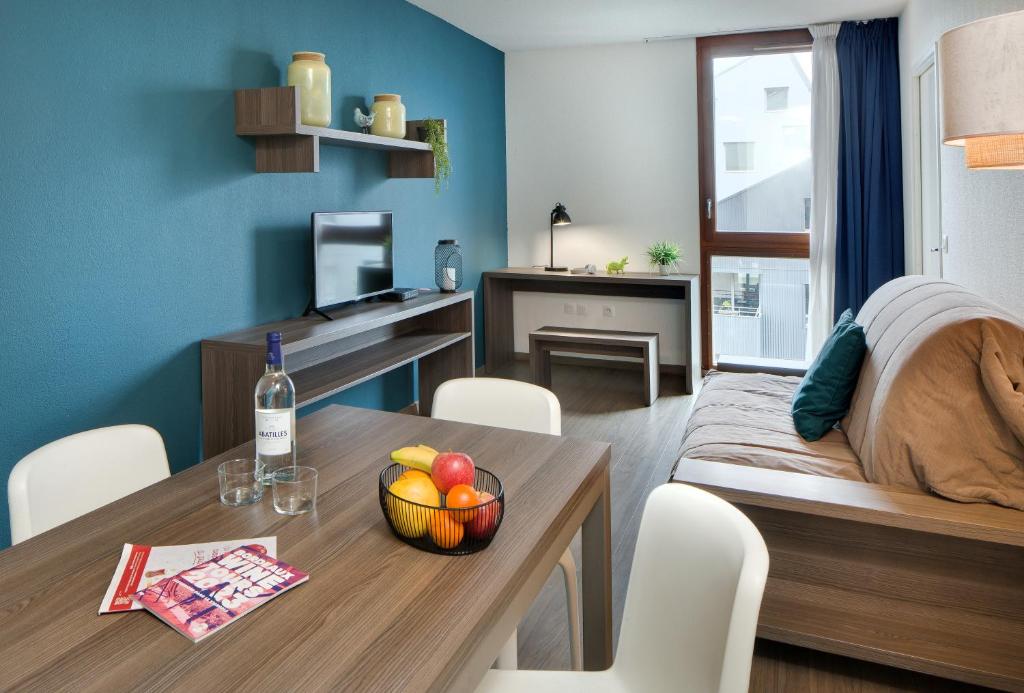 a room with a table with a bowl of fruit on it at Ténéo Apparthôtel Bordeaux Maritime - Cité du vin in Bordeaux