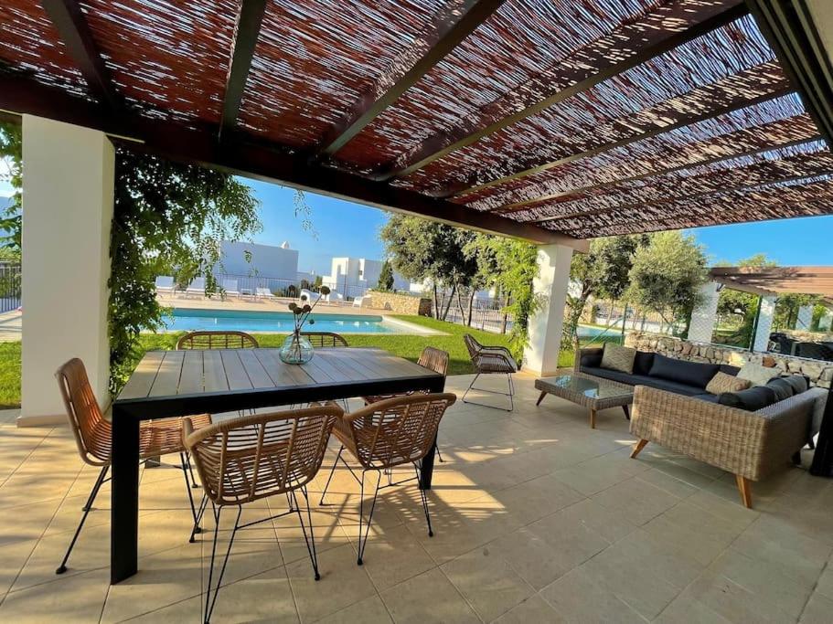 un patio con mesa y sillas bajo una pérgola en Villa con piscina privada y AC, en Sant Lluis