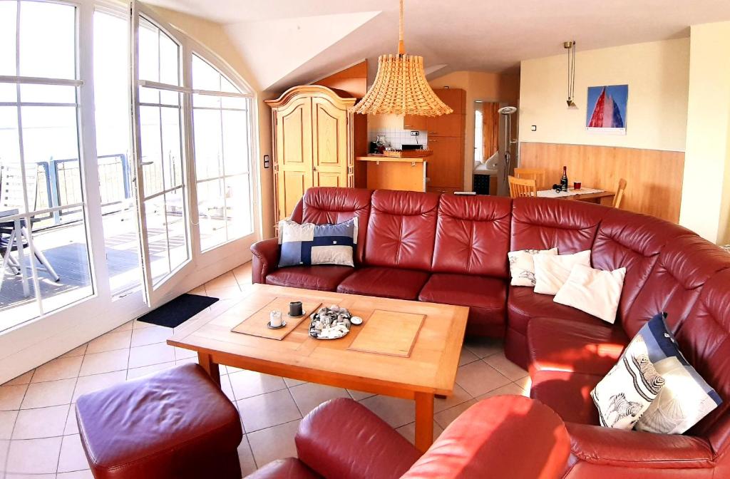 een woonkamer met een rode leren bank en een tafel bij Baltic View in Glowe