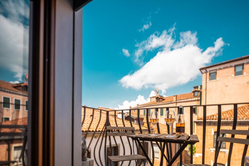 Un balcón con una mesa y copas de vino. en Saint Mark's view, en Venecia