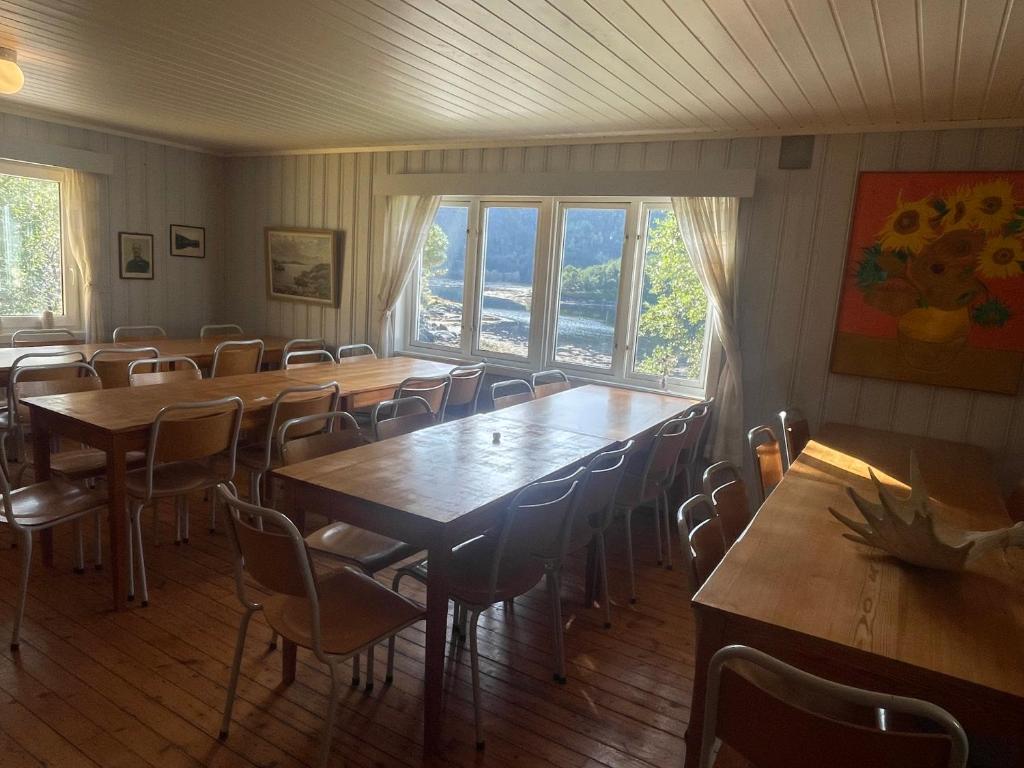 un comedor con mesas, sillas y ventanas en Unique totally private island in a Norwegian fjord with space for 40 people, a dinner room and a chapel, en Simle