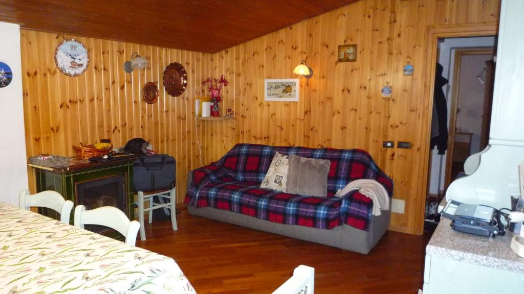 a living room with a couch in a room with wooden walls at campiglio; dedica a te la calda mansarda di pia in Madonna di Campiglio