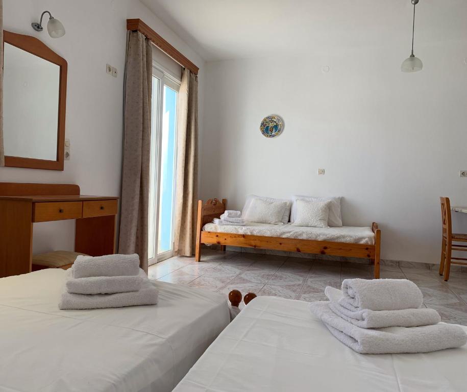 1 dormitorio con 2 camas, banco y espejo en Studios Fokia Beach en Amoopi