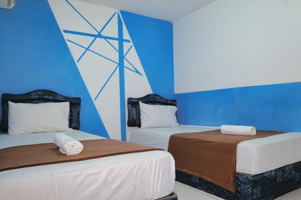 two beds in a room with blue walls at Hotel Olympic Jogyakarta by Sajiwa in Yogyakarta