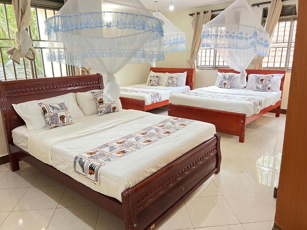 1 dormitorio con 3 camas en una habitación con ventanas en Victoria Rock Resort en Entebbe