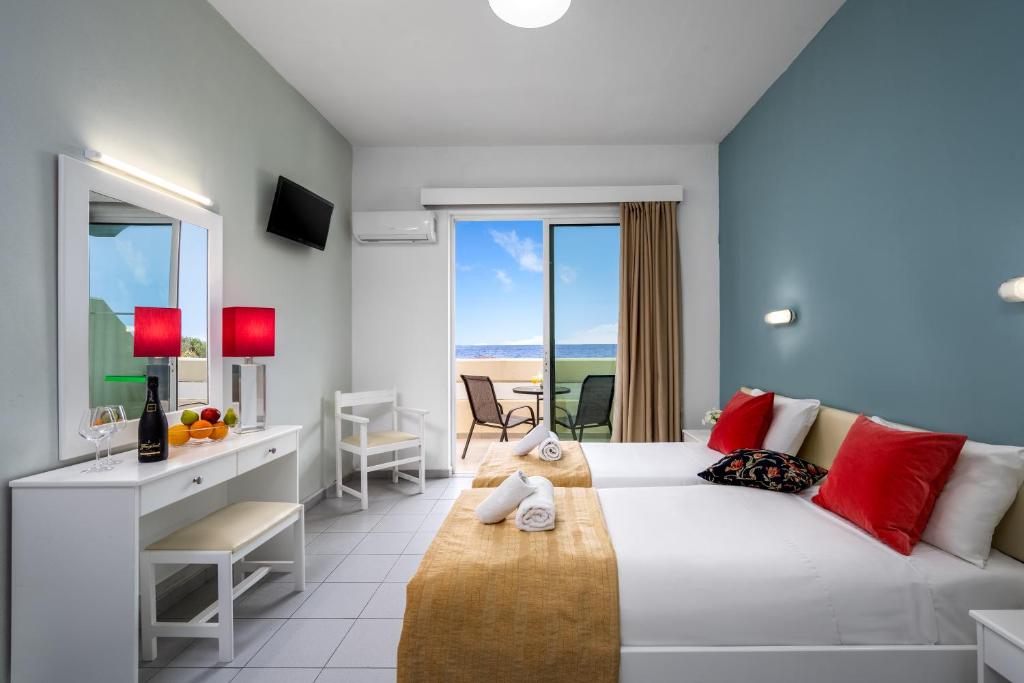 - une chambre avec un grand lit blanc et un bureau dans l'établissement Bayside Hotel Katsaras, à Kremasti