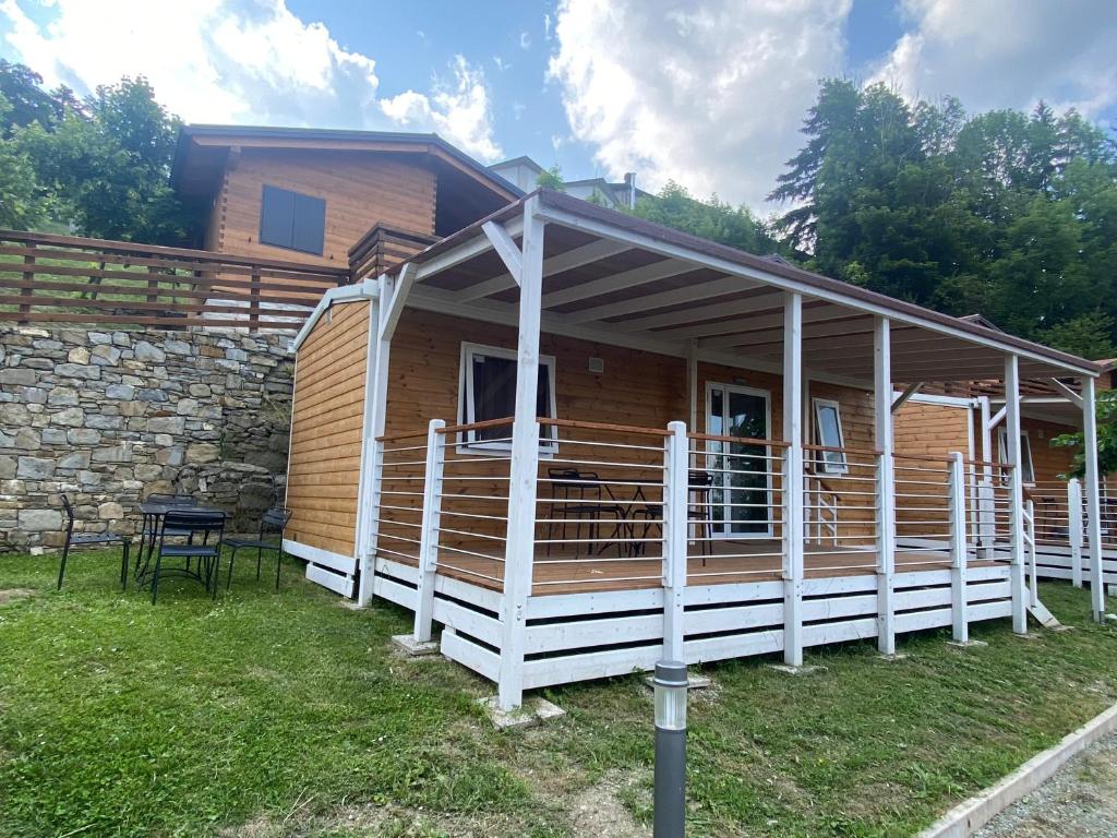 Cabaña de madera con porche y edificio en Camping Sestola, en Sestola