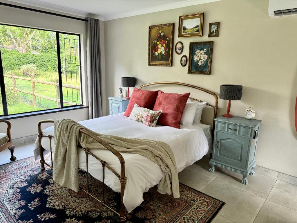 a bedroom with a bed with red pillows and a window at The Aloe Garden Cottage in Howick