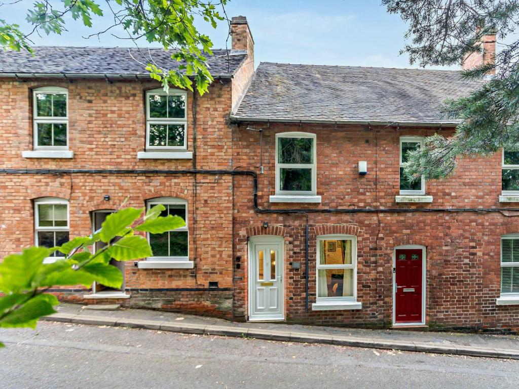 uma casa de tijolos com uma porta vermelha e janelas em 2 Bed in Ashbourne 85571 em Ashbourne