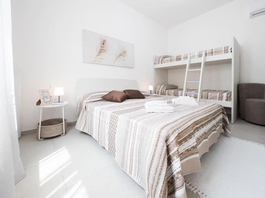 a white bedroom with a bed and two bunk beds at La Corte di Greta in Favignana