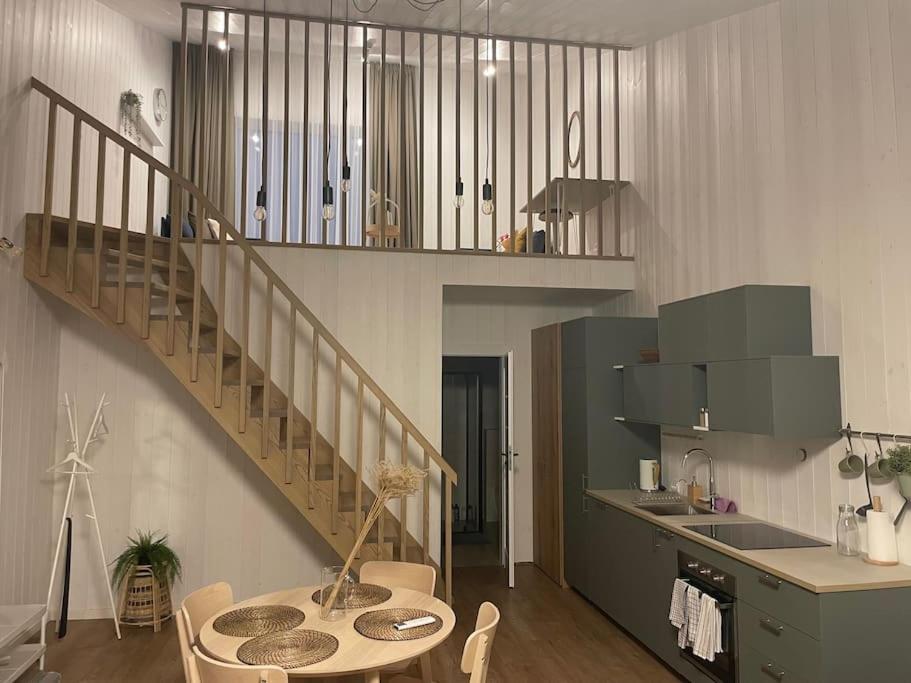 a kitchen with a staircase and a table in a room at Jaukūs apartamentai Svencelėje in Svenele