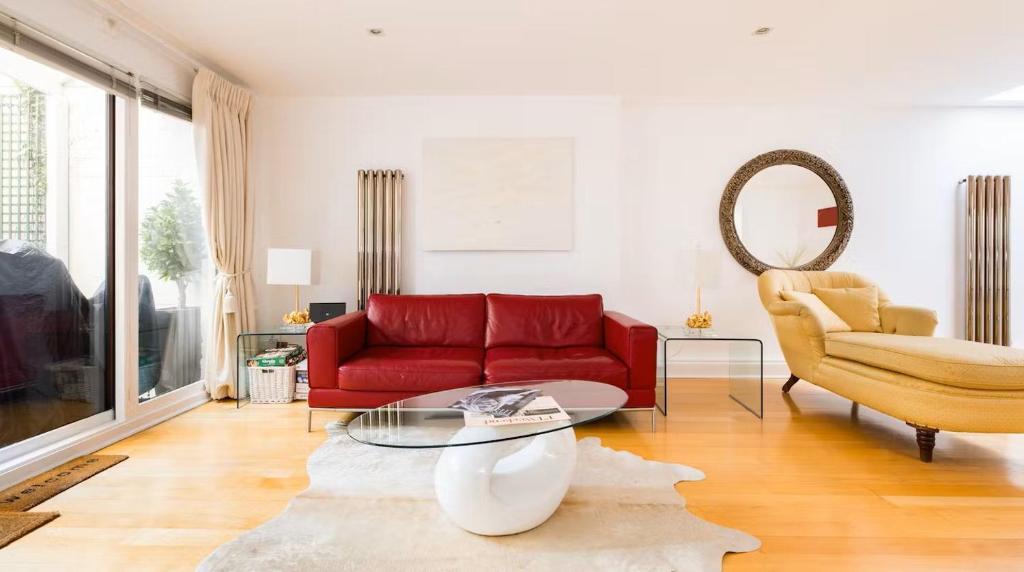 a living room with a red couch and a chair at Notting Hill Luxury Duplex in London