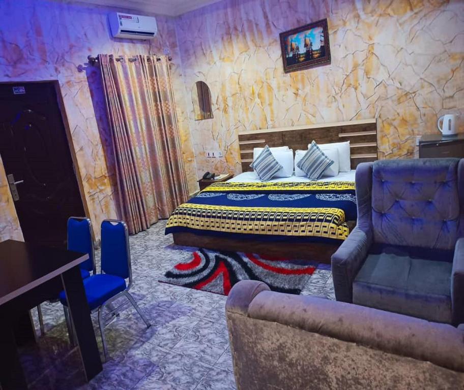 um quarto com uma cama, um sofá e uma cadeira em Joclarif Hotel and Suites em Zaria