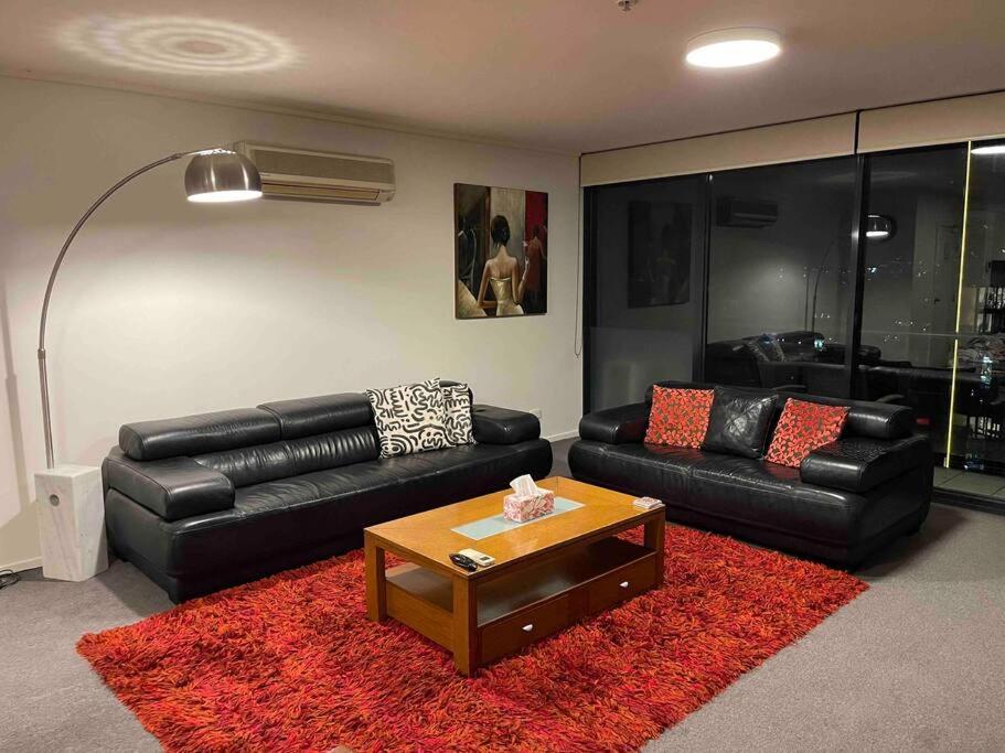 a living room with black leather couches and a red rug at Spacious 3 Bedroom Apartment Southbank in Melbourne