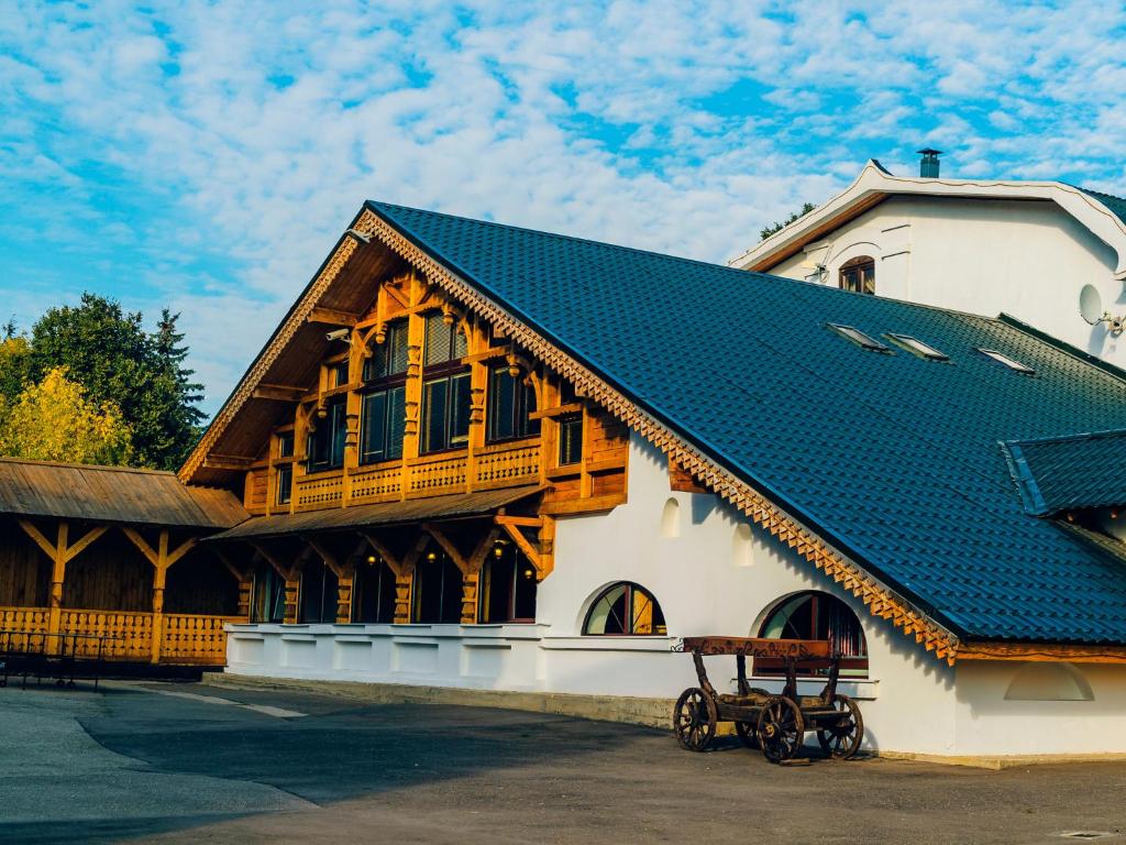 um edifício com um telhado azul com um banco à frente em Usadba Romashkovo Hotel em Romashkovo