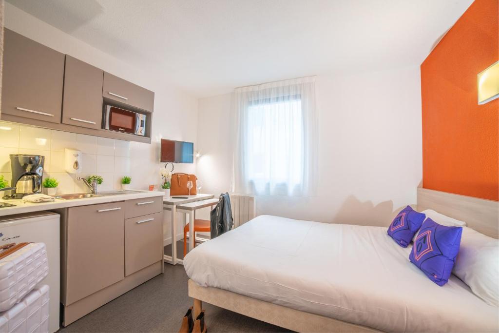 een kleine kamer met een bed en een keuken bij Montempô Apparthôtel Paris-Vélizy in Vélizy-Villacoublay