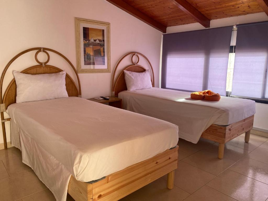 2 bedden in een kamer met 2 bedden, waarvan 1 tweepersoonsbed en 1 eenpersoonsbed. bij Aparthotel Praia Baixo in São Tiago