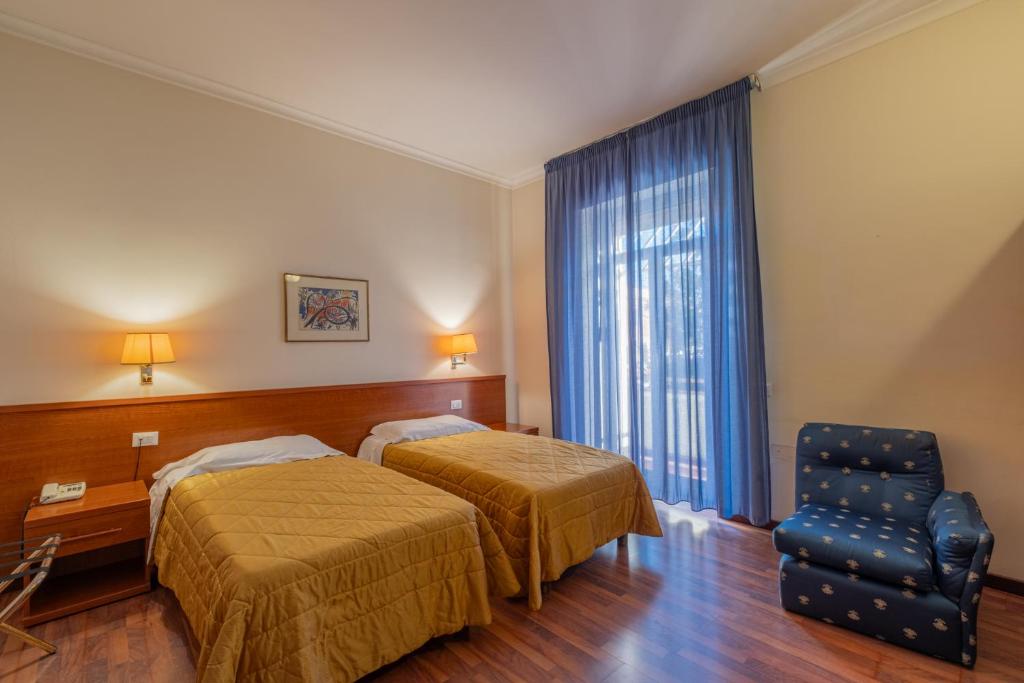 a hotel room with two beds and a chair at Hotel Monte Verde in Rome