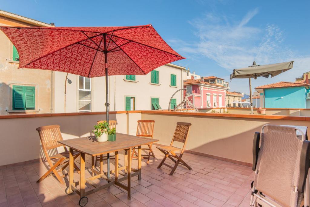 eine Terrasse mit einem Tisch, Stühlen und einem Sonnenschirm in der Unterkunft Casa Cellini - Piombino Apartments in Piombino