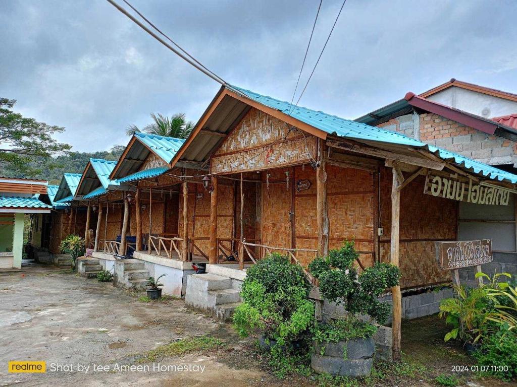 a wooden house with a blue roof at Ameen Homestay อามีน โฮมสเตย์ in Ban Komo Sam Sip Paet