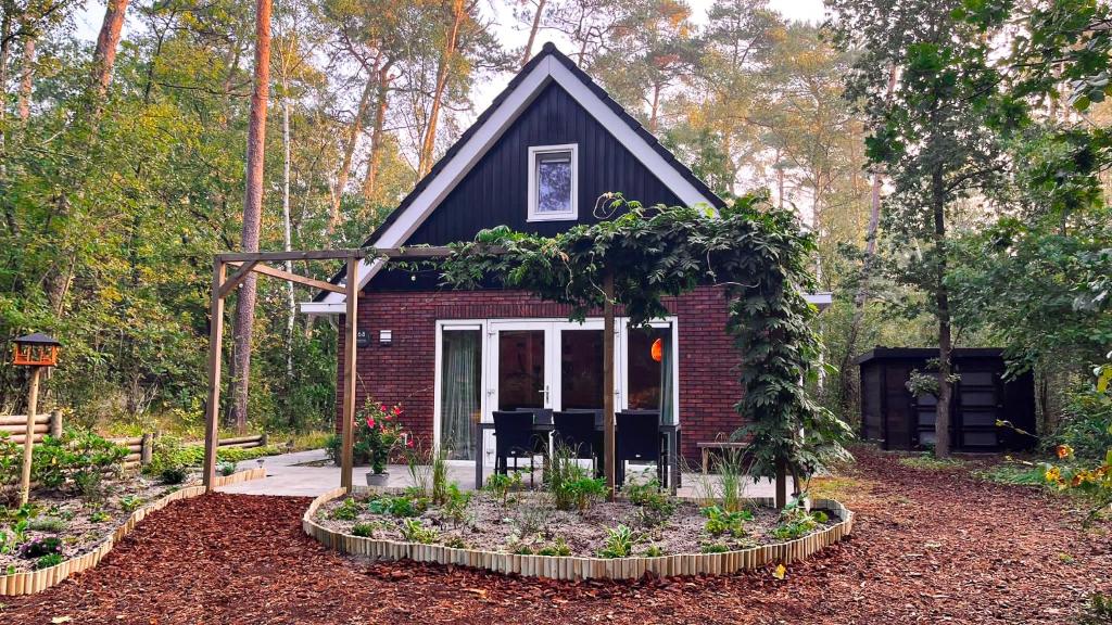 une petite maison avec un jardin en face de celle-ci dans l'établissement Vakantiehuis Vliegend Hert Veluwe, à Nunspeet