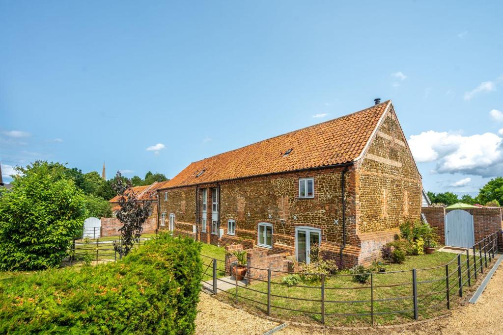 an old brick house with a fence around it at Christmas Barn in Snettisham