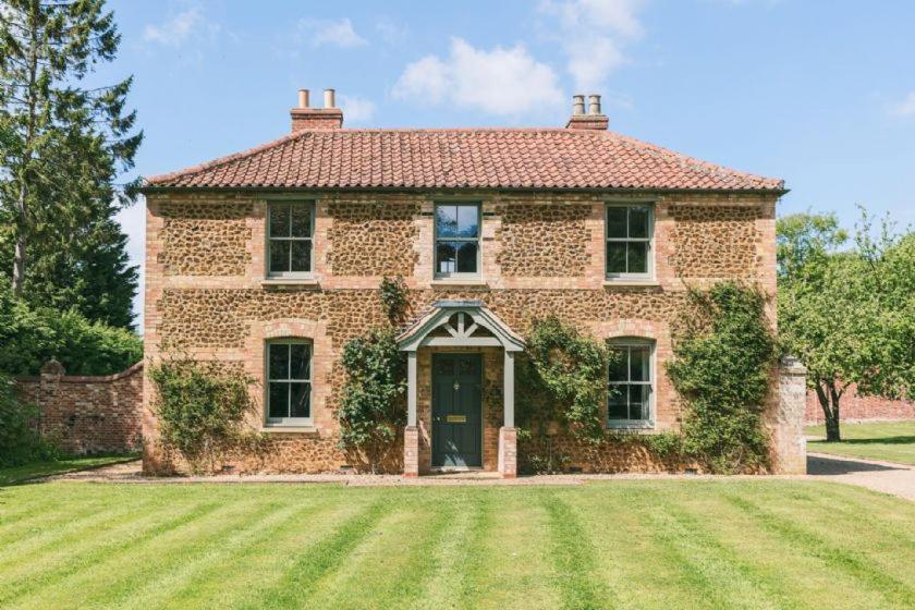 a large brick house with a large grass yard at Cottages in the Walled Garden in Sedgeford