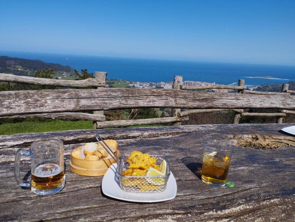 una mesa con un tazón de comida y dos vasos de cerveza en Arrantzale Beach, en Bermeo