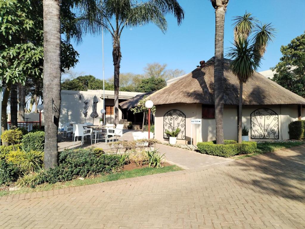 a building with a thatched roof with palm trees at Hole In One in Roodepoort