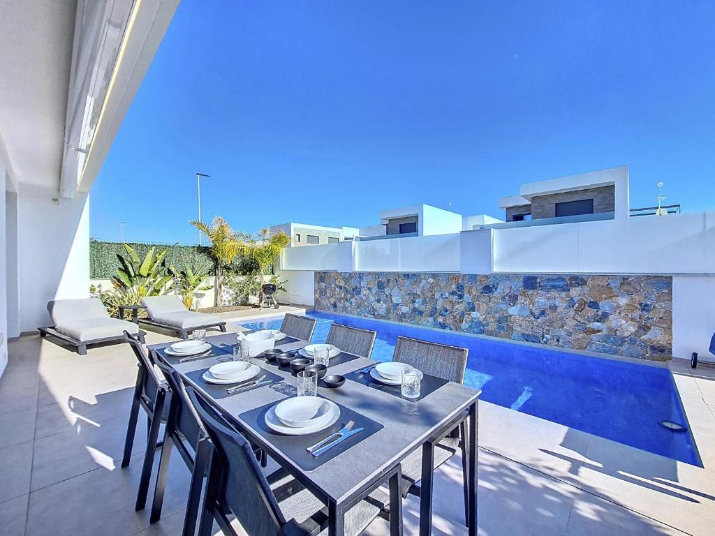 uma sala de jantar com mesa e cadeiras e uma piscina em Villas Alejandra - 8309 em Santiago de la Ribera