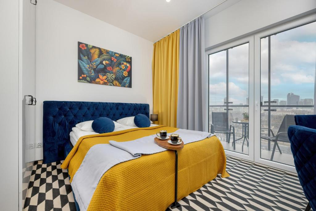 a hotel room with a yellow bed and a balcony at Business Center Apartments Warsaw Wola by Renters in Warsaw