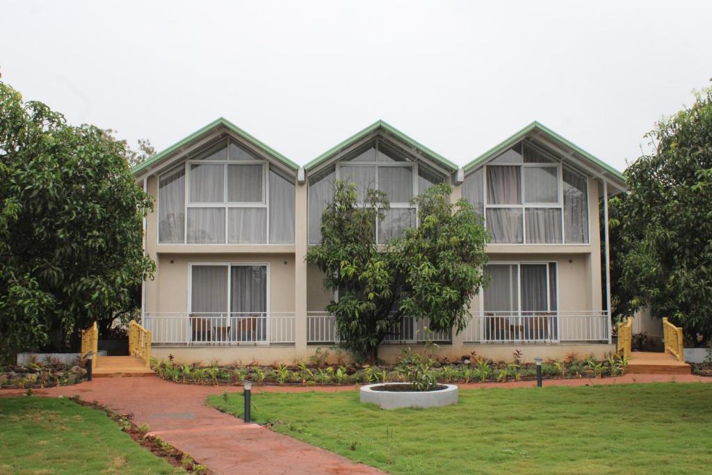 une grande maison avec des arbres devant elle dans l'établissement Mango Leaf Lake Resort, à Pune