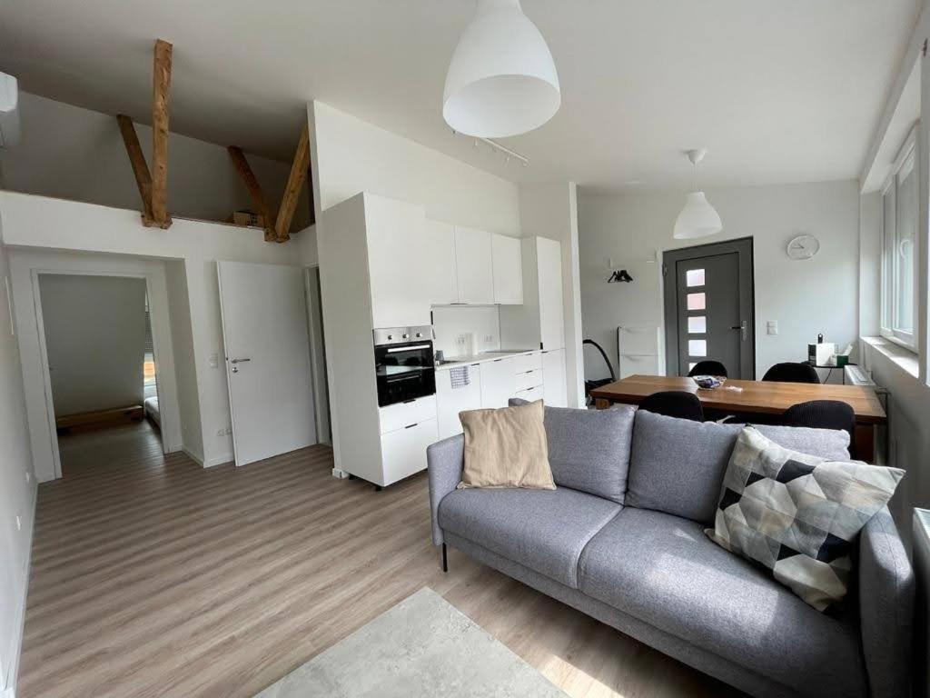 uma sala de estar com um sofá cinzento e uma cozinha em Apartment near Parndorf 