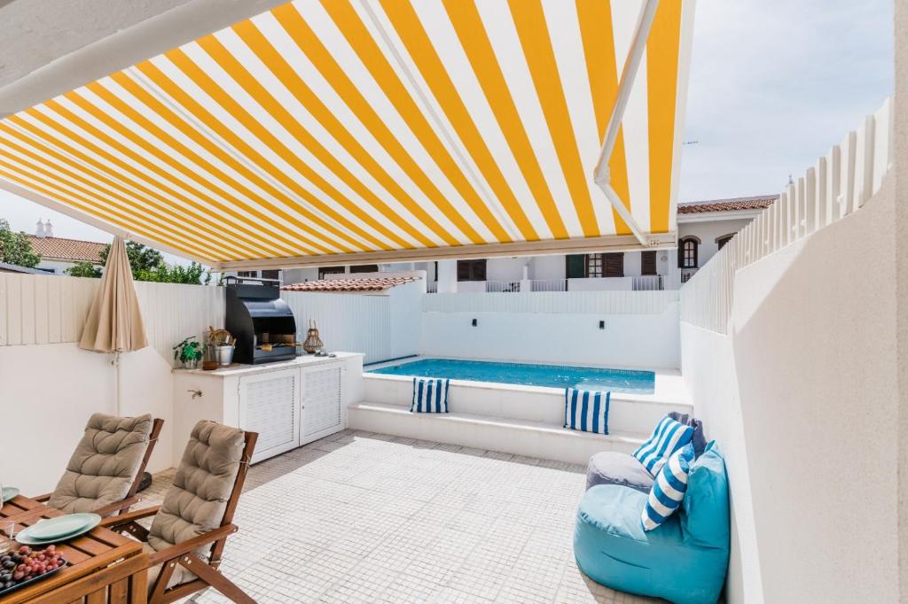 a patio with a swimming pool and a yellow and white umbrella at StaySalty - Resort Style Family Beach House with Pool in Altura