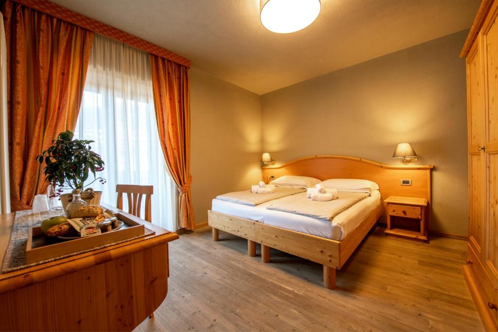 - une chambre avec un lit, une table et une fenêtre dans l'établissement Hotel Diffuso Locanda Elisa, à Dimaro