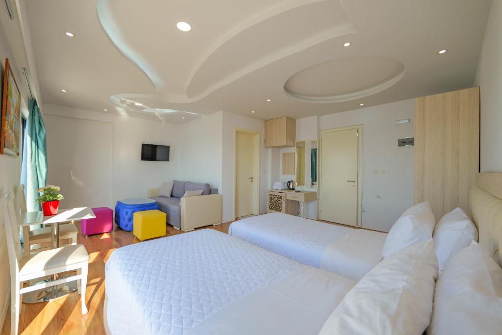 a bedroom with two beds and a living room at Hotel Iliria in Sarandë