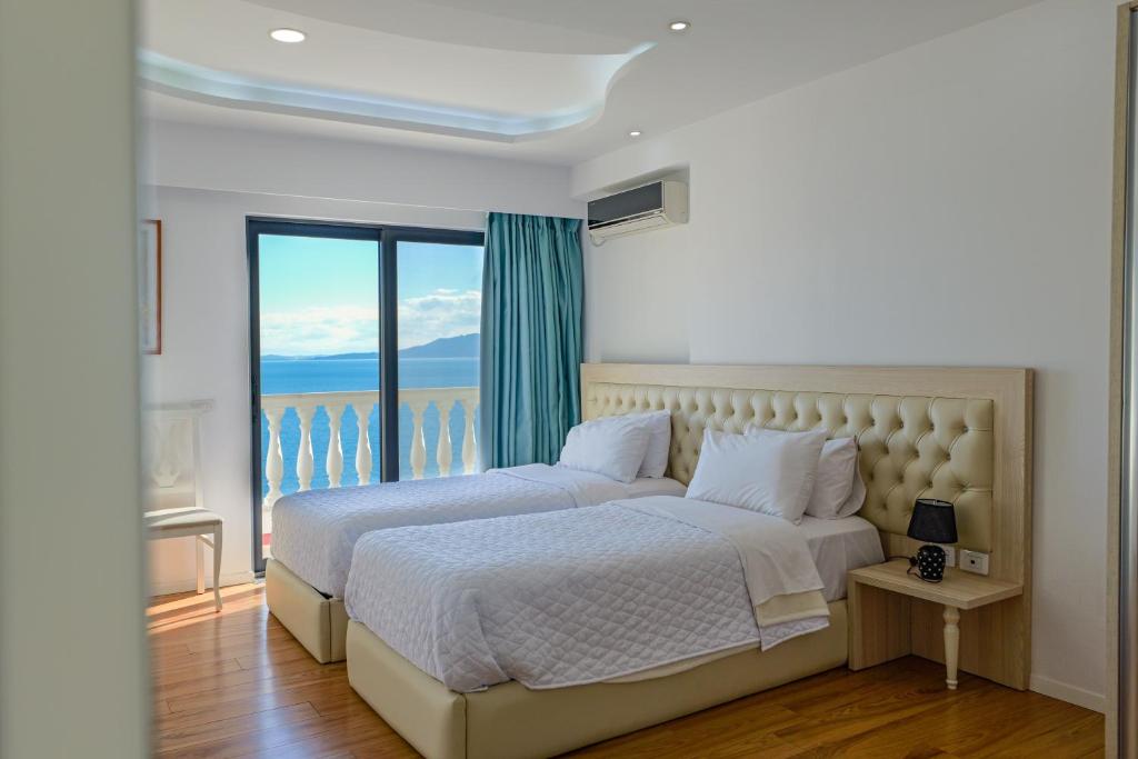 a bedroom with two beds and a large window at Hotel Iliria in Sarandë