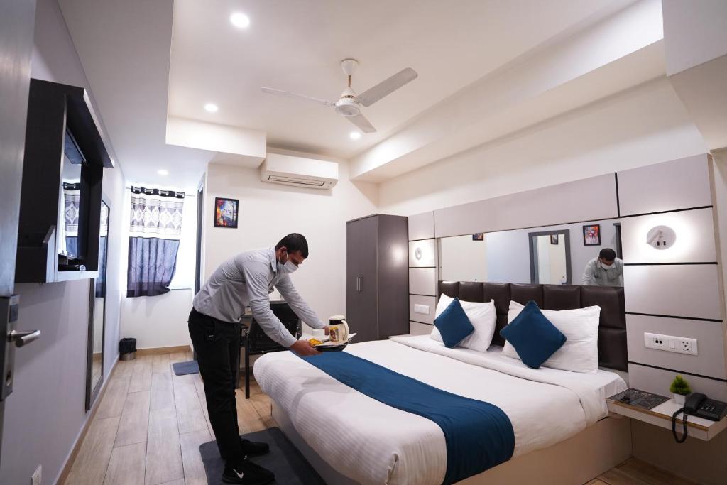 un hombre está haciendo una cama en una habitación de hotel en Hotel Lyf Corporate Suites - Kirti Nagar en Nueva Delhi