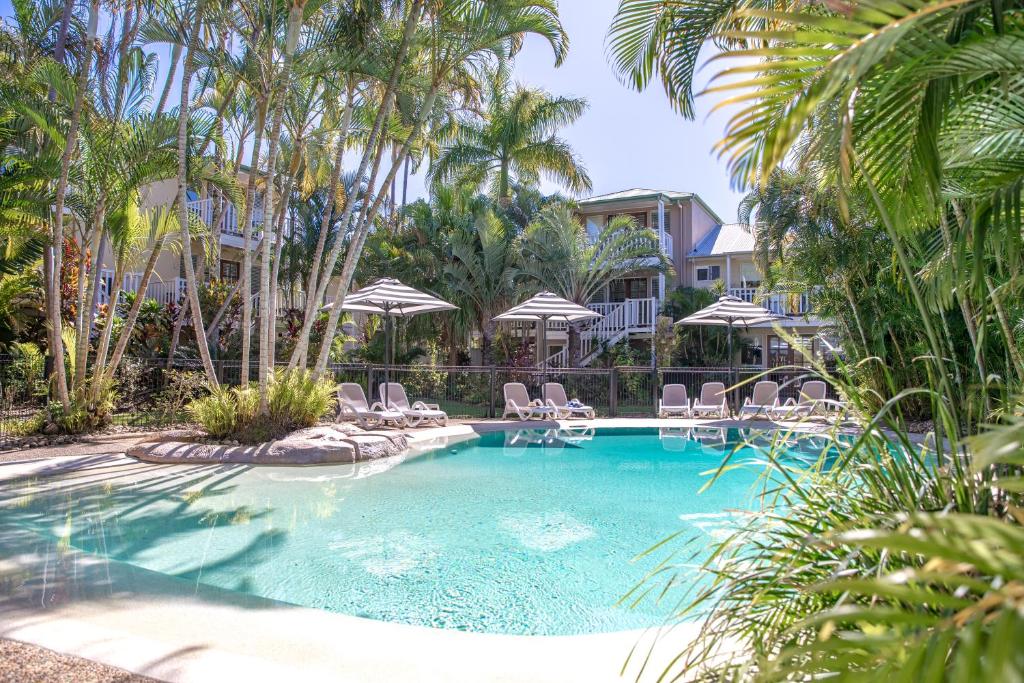 a swimming pool with chairs and umbrellas at Sandy Beach Resort in Noosaville