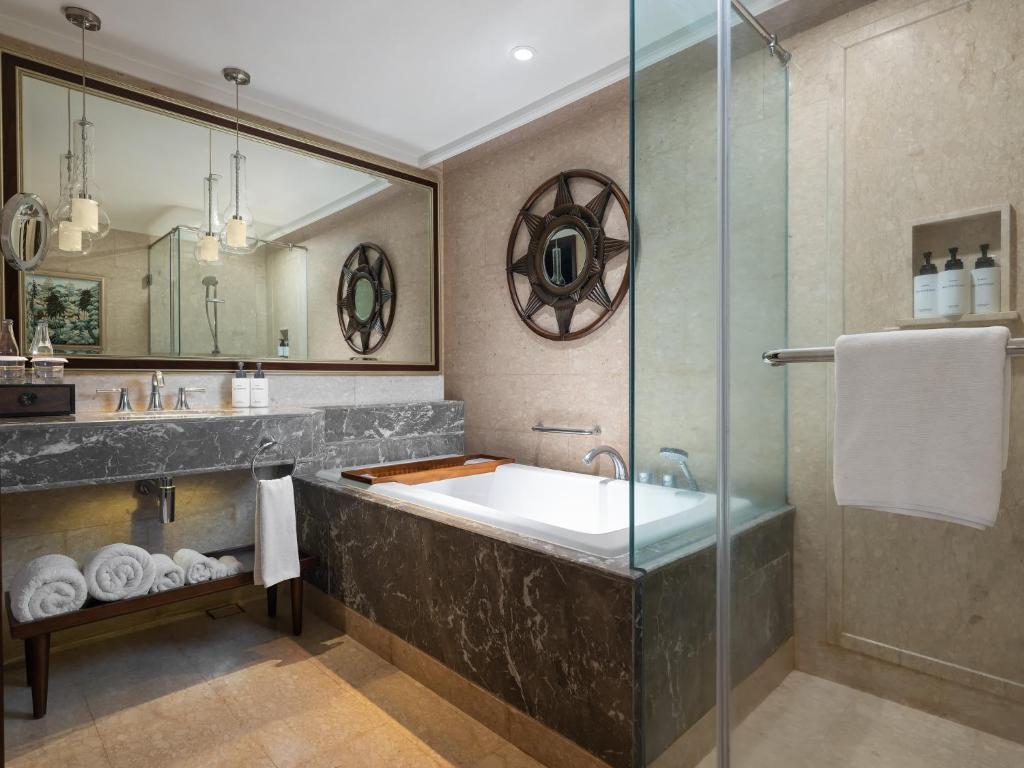 a bathroom with a tub and a glass shower at InterContinental Bali Resort by IHG in Jimbaran
