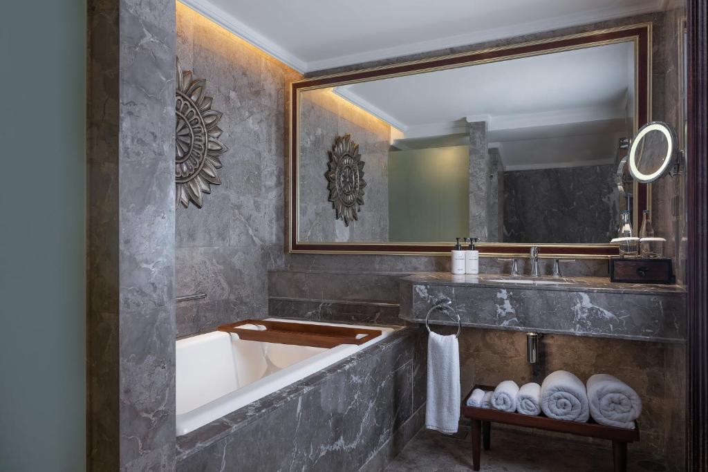 a bathroom with a tub and a sink and a mirror at InterContinental Bali Resort by IHG in Jimbaran