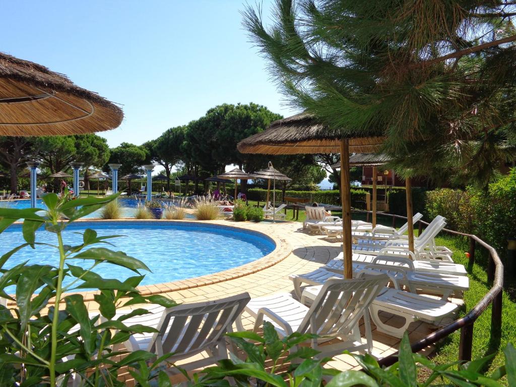 einen Pool mit Stühlen und Sonnenschirmen in einem Resort in der Unterkunft Bicos 101 by Check-in Portugal in Albufeira