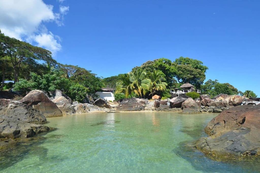 a body of water with rocks and trees at Eco Lodge Cristal Nosy Komba in Nosy Komba