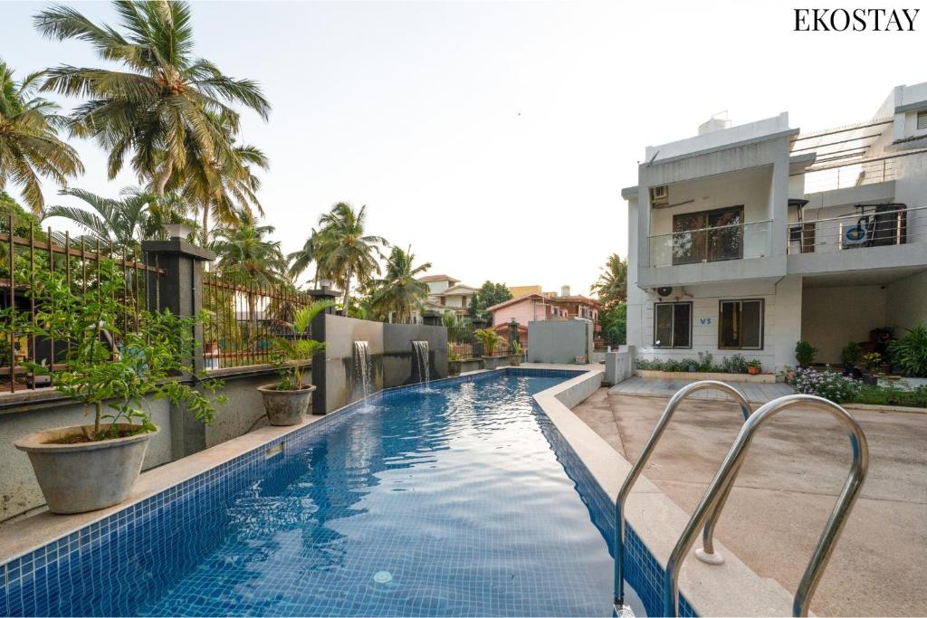 a swimming pool in front of a building at EKOSTAY - Bliss Apartment in Candolim