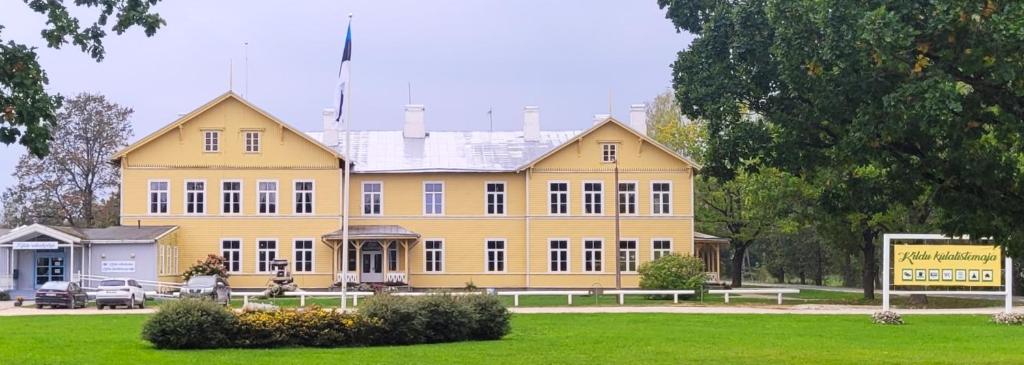 a large yellow building with benches in front of it at Kildu külalistemaja in Kildu