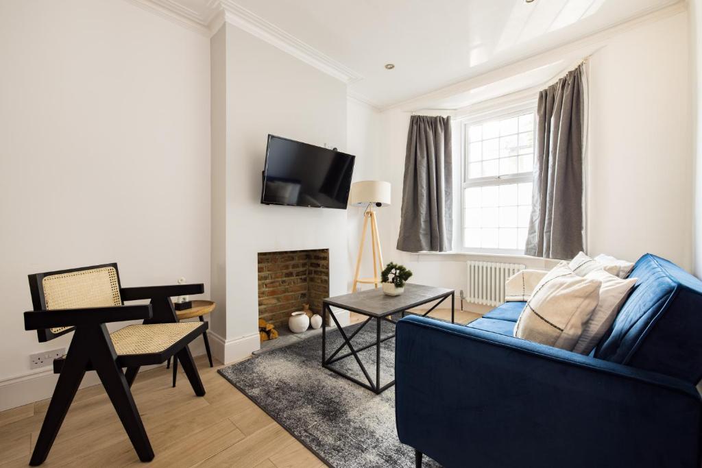 a living room with a blue couch and a piano at The Stratford Villas in London