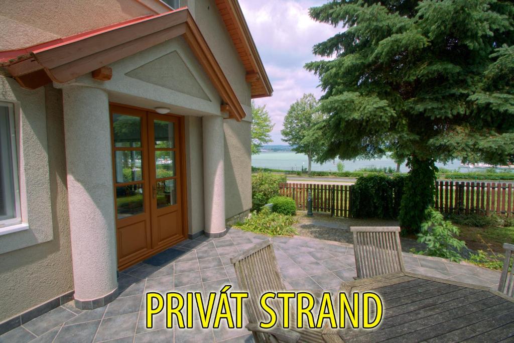 a porch of a house with two chairs and a door at Aquilo Apartmanok in Tihany